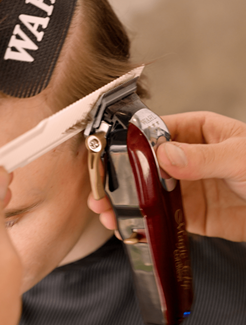 Barber using a Wahl Magic Clip Cordless to clip model's hair.